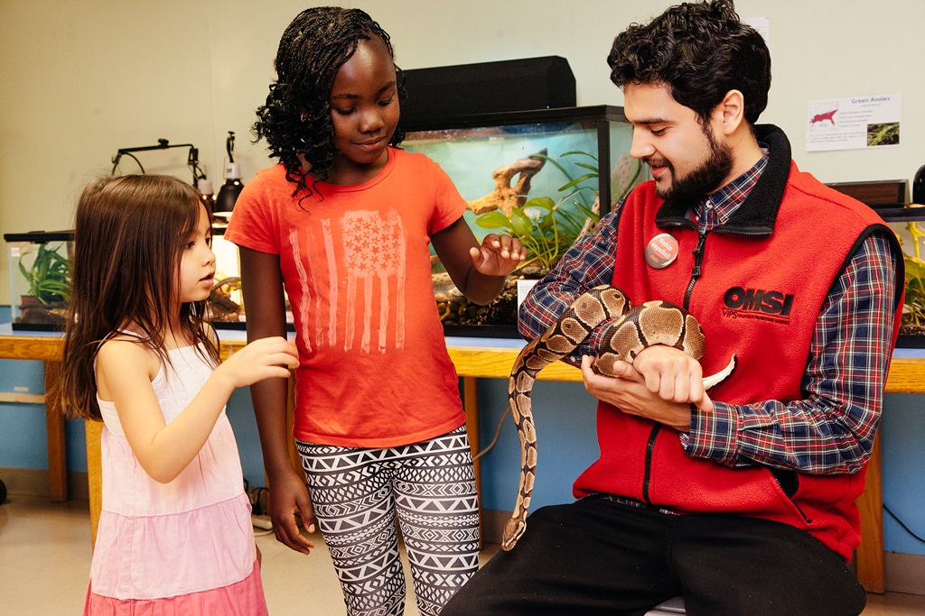 OMSI volunteer showing two children a reptile in the Life Lab.