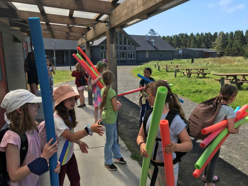 Students playing with pool noodles at Camp Gray.