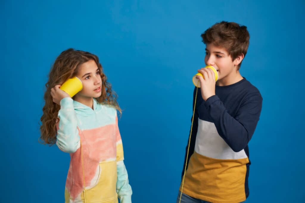 kids listening and talking through a paper cup phone