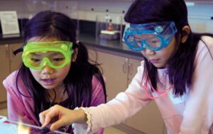 Two students wearing googles conducting a chemistry experiment.