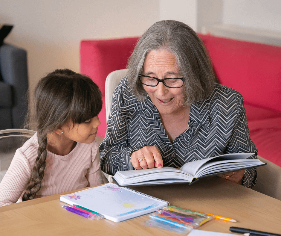 Grandma reading to granddaughter at a table