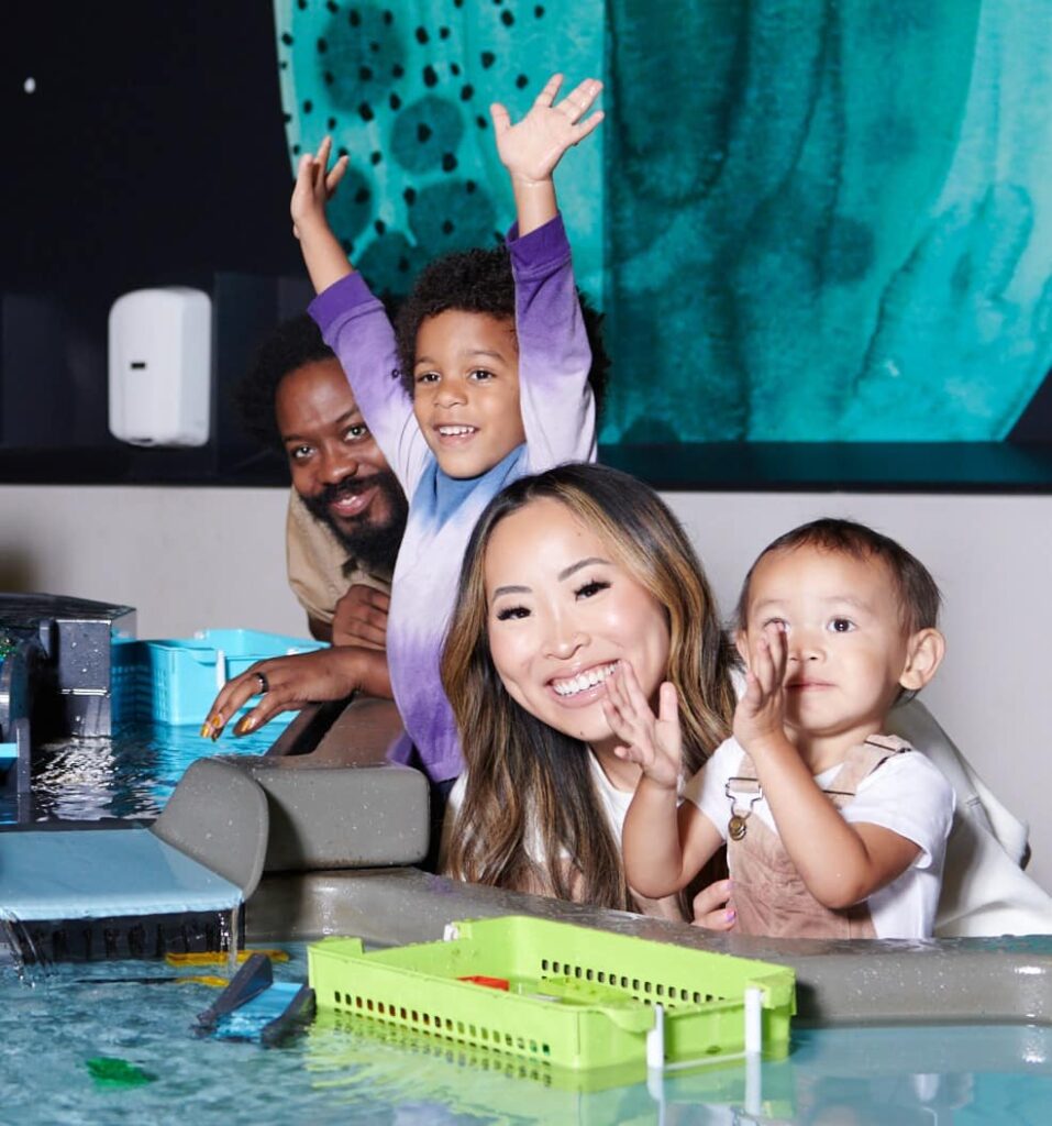 Group of parents and toddlers playing with water in the science playground at OMSI