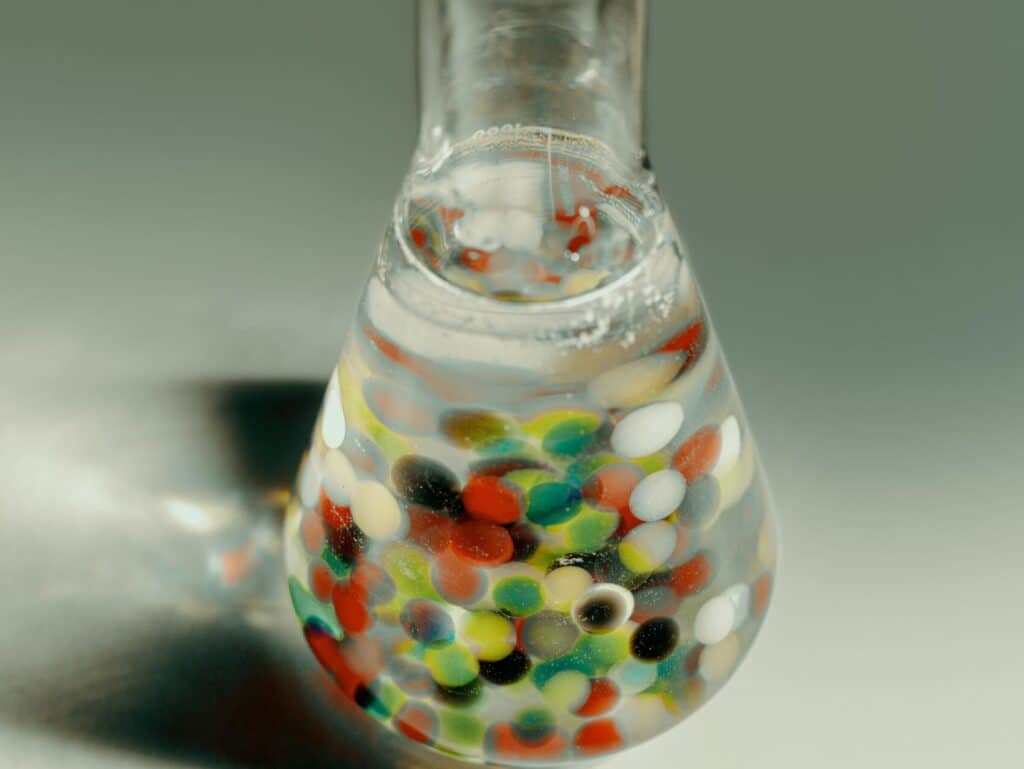 Chemistry narrow neck flask filled with water and colorful beads.
