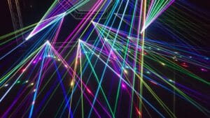 Colorful lasers beam out from the darkness.