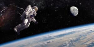An astronaut in full spacesuit tethered to unseen craft on spacewalk above Earth with moon visible in the background. Astronaut is 3D render with following images used from NASA: