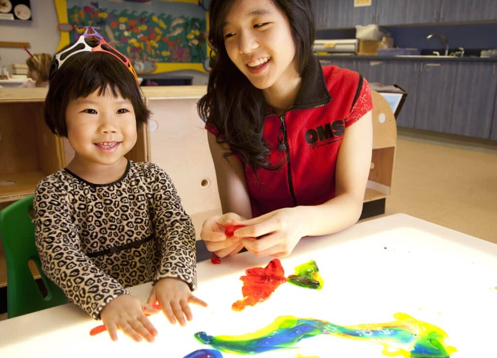 OMSI Volunteer and little girl playing with flubber in the science playground