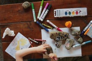 Overhead view of a table with watercolors, markers and other art supplies.