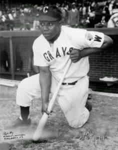 Josh Gibson kneeling with baseball bat during a game