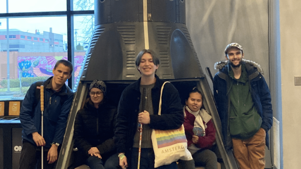 A group of students from the Washington State School for the Blind pose in front of the space capsule during their museum visit.