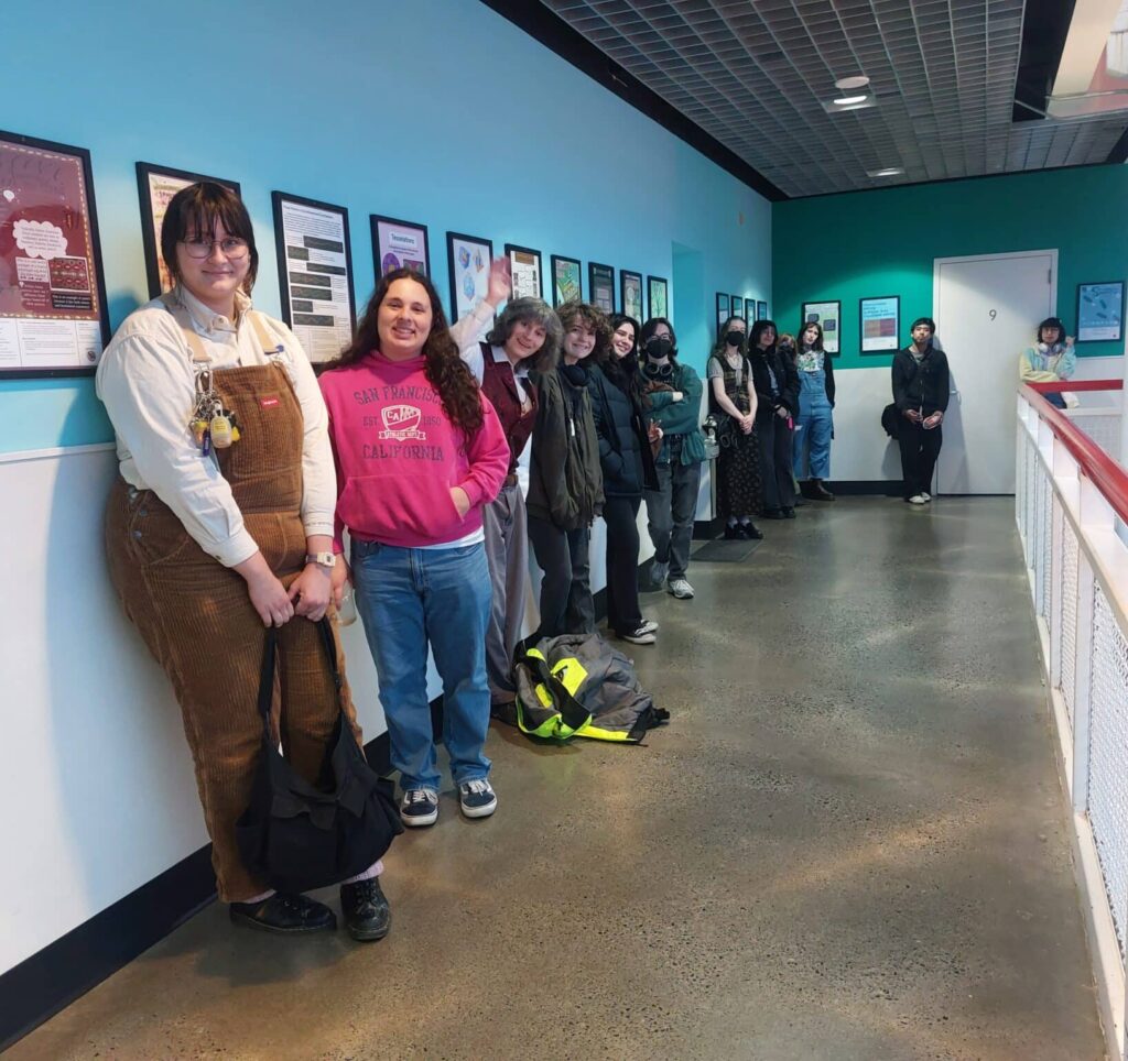 Students from the Fall 2024 Visual Mathematics class at PNCA pose beside their final posters at OMSI.