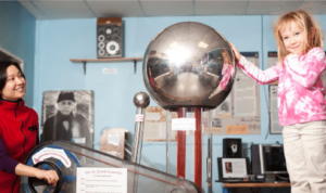 Little girl touching a metal sphere making her hair staticky in the physics lab