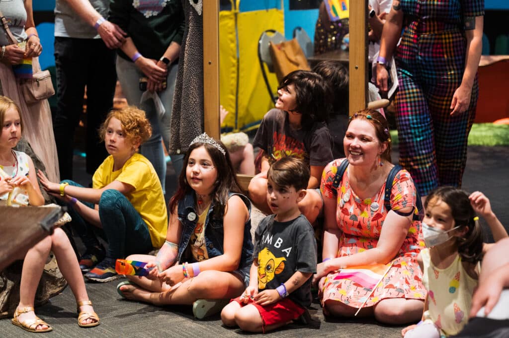 A group of kids watch a performance during Pride at the Museum