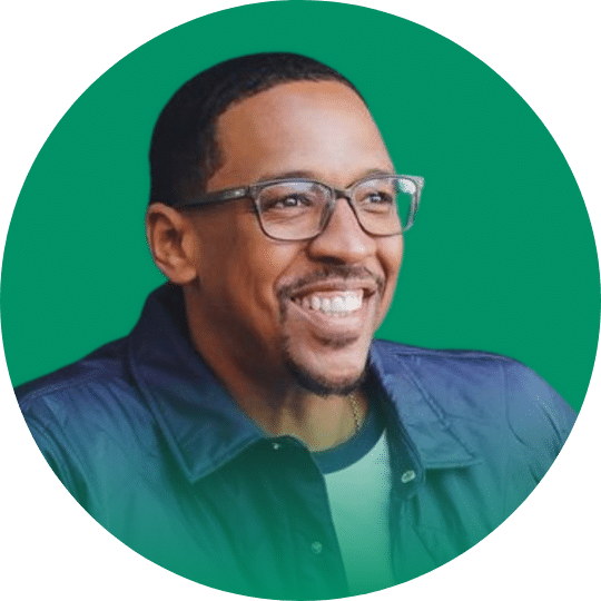 Headshot of a Former Blazer, Channing Frye, wearing glasses and a denim button down