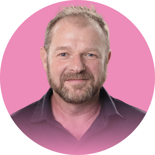 Headshot of a man with a blonde beard and a black polo shirt