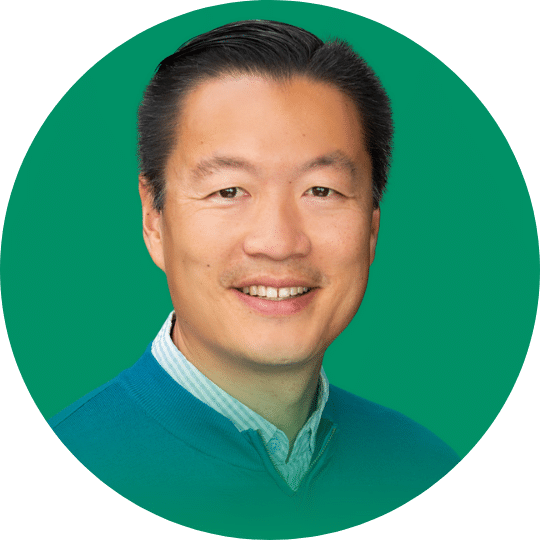 Headshot of a Man wearing a blue sweater over a button down