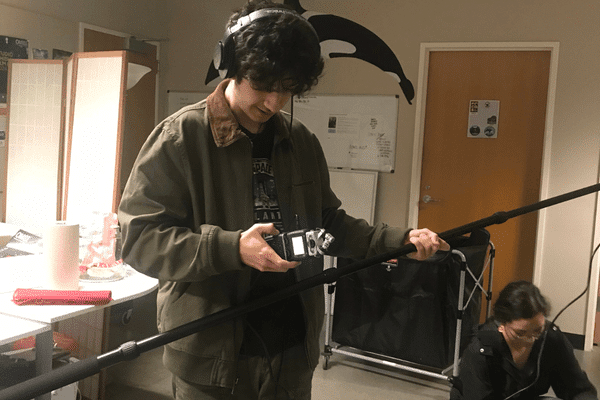 Teen holding a mic and looking at the sound monitor