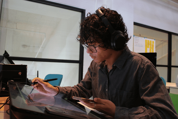 Teen with headphones on using a digital drawing pad