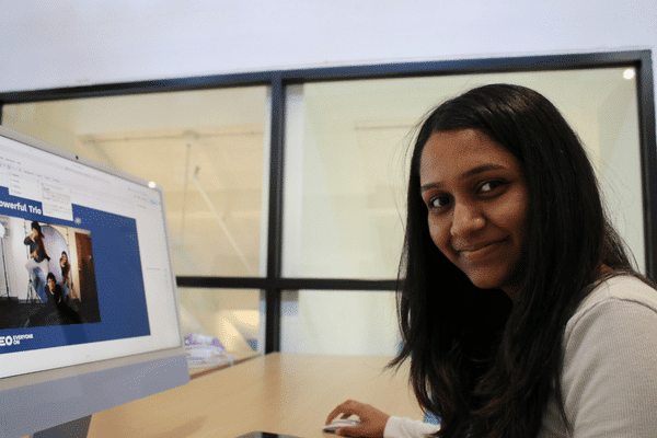 Teen looking at the camera while using a desktop computer in the teen tech center