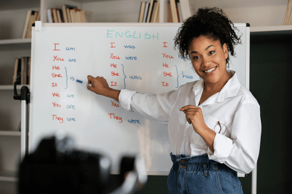Woman in dress clothes pointing to words on a white board during a meeting