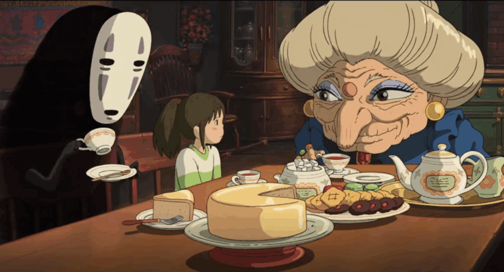 No Face and Chihiro sit at a table covered with food.