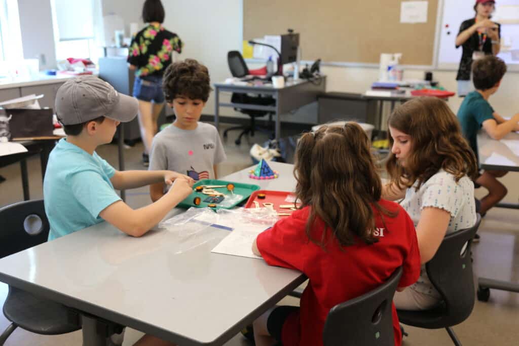 Students in OMSI 's summer day camp sitting around a table working on a science experement.