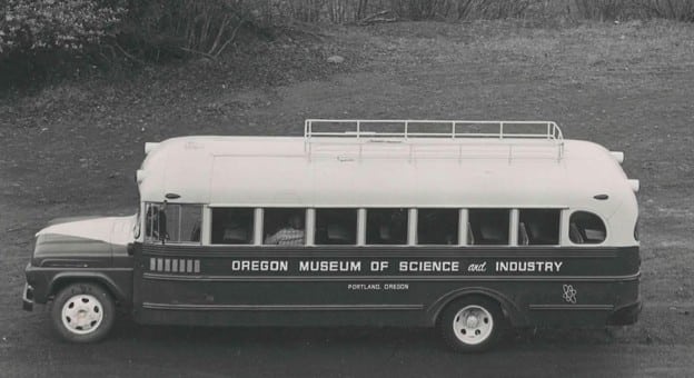 Black and white photo of an old bus that says Oregon Museum of Science and Industry