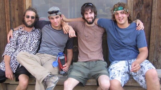 Four OMSI camp counselors sit on a bench at Camp Hancock with their arms wrapped around each other