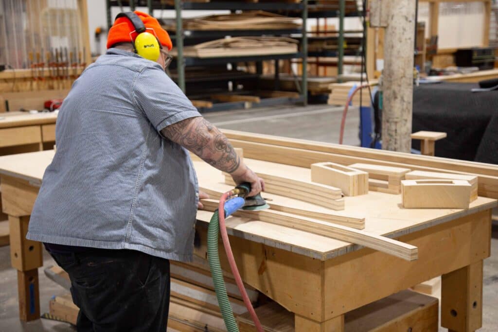 A person in OMSI's EXLAB sands down wooden blocks to use in exhibit fabrication.