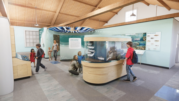 A rendering created by the OMSI Creative Services team for a new visitor center for the McKenzie River Discovery Center. The image includes rendered people and families for scale and interactive exhibits highlighting features of the McKenzie subbasin.