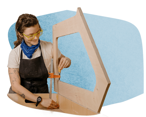 An image of a fabricator from OMSI's EXLAB working on an exhibit with a blue rounded shape behind them
